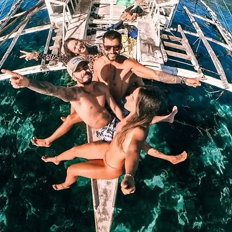 A BSL group sitting together on the front of a boat over clear water in Coron, Philippines